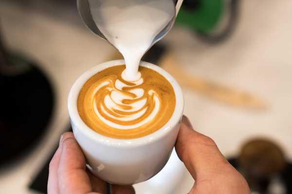 Pouring frothed milk into an espresso coffee cup